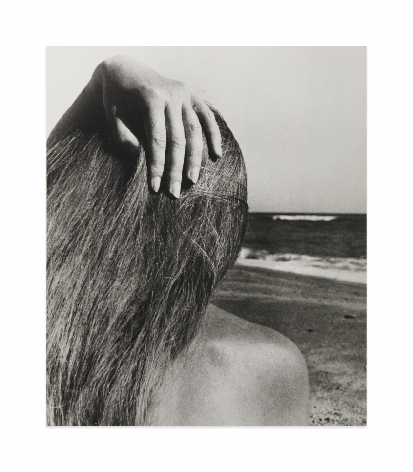 Black and white photograph by Bill Brandt showing the back of the head of a female figure on the beach 