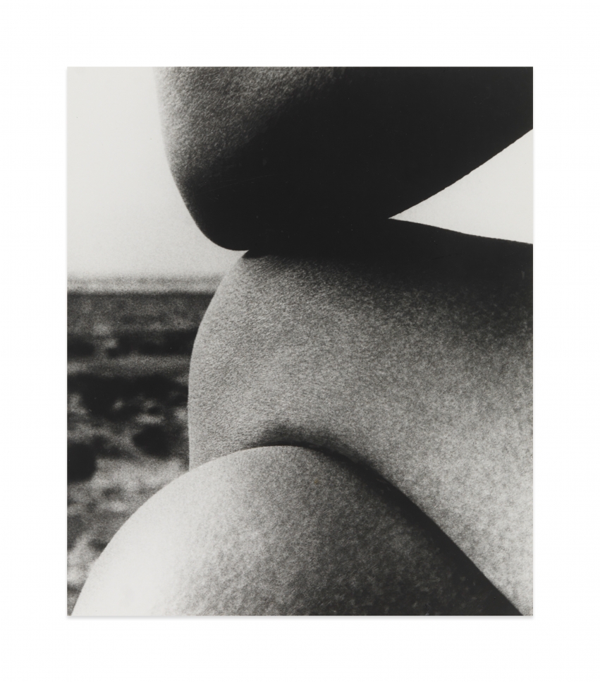 Black and white photograph by Bill Brandt showing the crossed legs of a nude figure on the beach